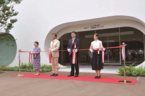 入口前でテープカットを行なっている写真