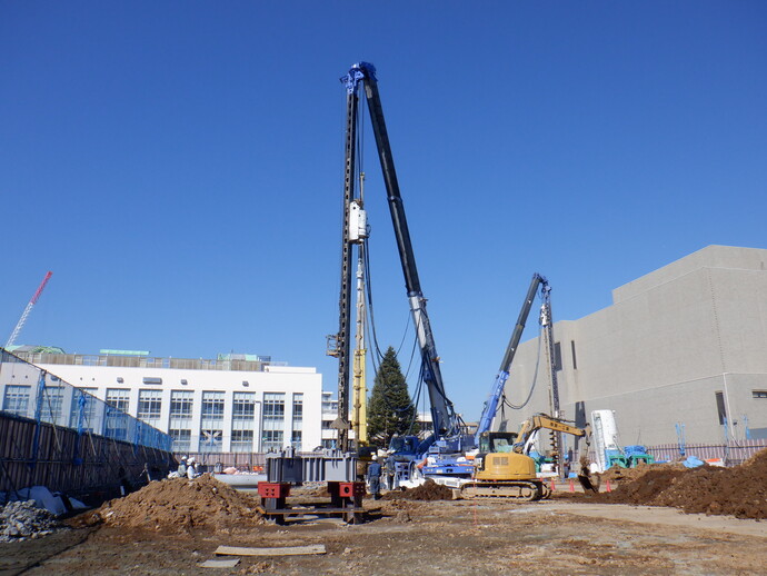 写真: 工事現場に一台の工事車両が入っています。穴に杭を打ち込んでいました。