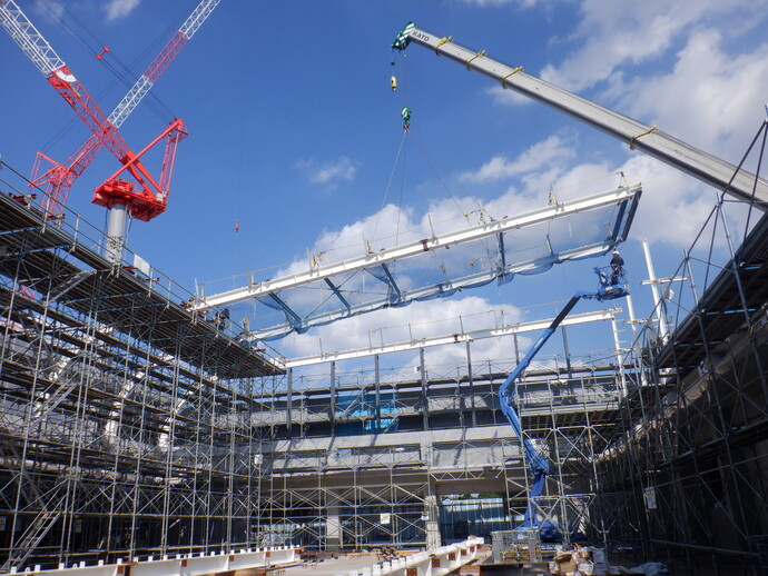 写真：屋根の部材をクレーンで移動させています。