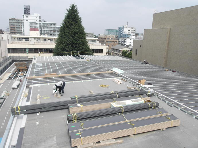 写真:体育館棟の金属屋根設置作業を行っていました。
