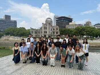 広島の原爆ドームの対岸で研修事業に参加した若者たちが並んでいる集合写真